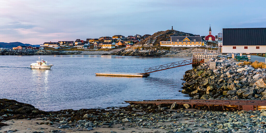 Motorboat arriving to a dock in a small harbour with Nuuk Cathedral in the distance,Nuuk,Sermersooq,Greenland