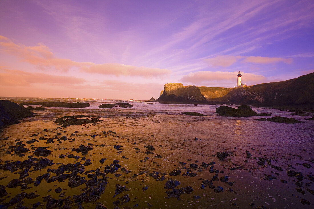 Yaquina Head Light und Ebbe am Ufer entlang der Küste von Oregon bei Sonnenuntergang, Oregon, Vereinigte Staaten von Amerika