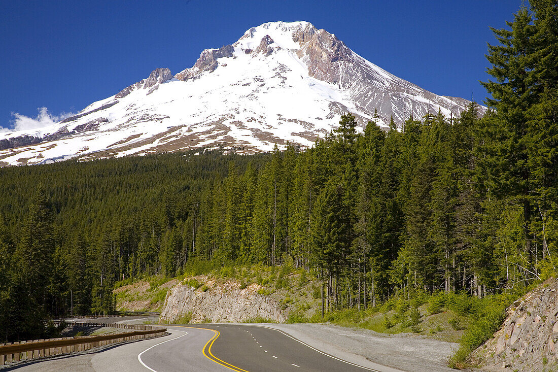 Schnee bedeckt einen majestätischen Mount Hood mit einem dichten Wald, der den Highway und den Berghang säumt, Mount Hood National Forest, Oregon, Vereinigte Staaten von Amerika