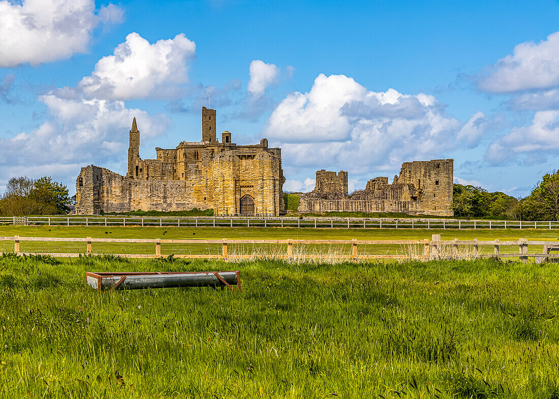 View of medieval,Warkworth Castle ruins beyond the cricket field in the village of Warkworth on a sunny day,Northumberland,England,United Kingdom