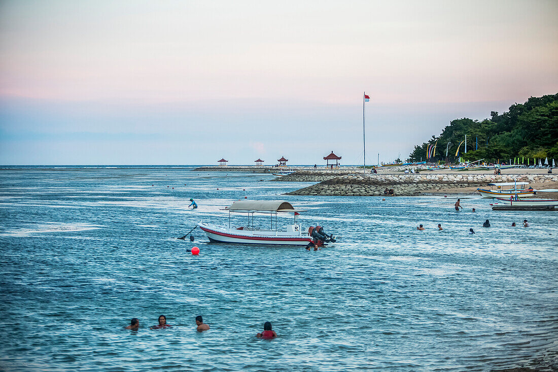 Locals enjoy a Bali sunset while swimming in the water,Mount Agung looms in the distance,Sanur,Bali,Indonesia