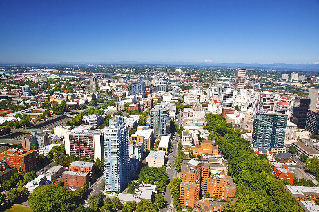 Aerial view of a cityscape of Portland,Oregon with roadways and bridges across the Willamette River,Mount Saint Helens and Mount Tabor in the distance along the horizon and blue sky,Portland,Oregon,United States of America