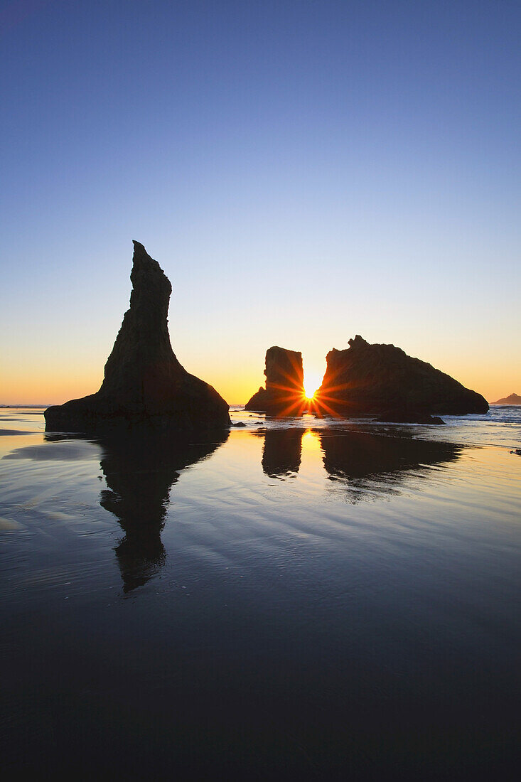 Silhouettierte Felsformationen am Bandon Beach bei Sonnenuntergang und Ebbe,Oregon-Küste,Oregon,Vereinigte Staaten von Amerika
