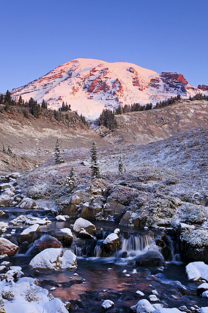 Stream flowing from snow-covered Mount Rainier at sunrise in Mount Rainier National Park,Washington,USA