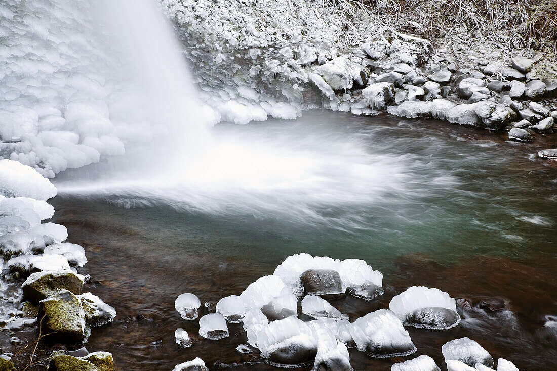 Nahaufnahme eines Wasserfalls, der im Winter in einen Bach plätschert, mit schneebedeckten Felsen, Pazifischer Nordwesten, Oregon, Vereinigte Staaten von Amerika