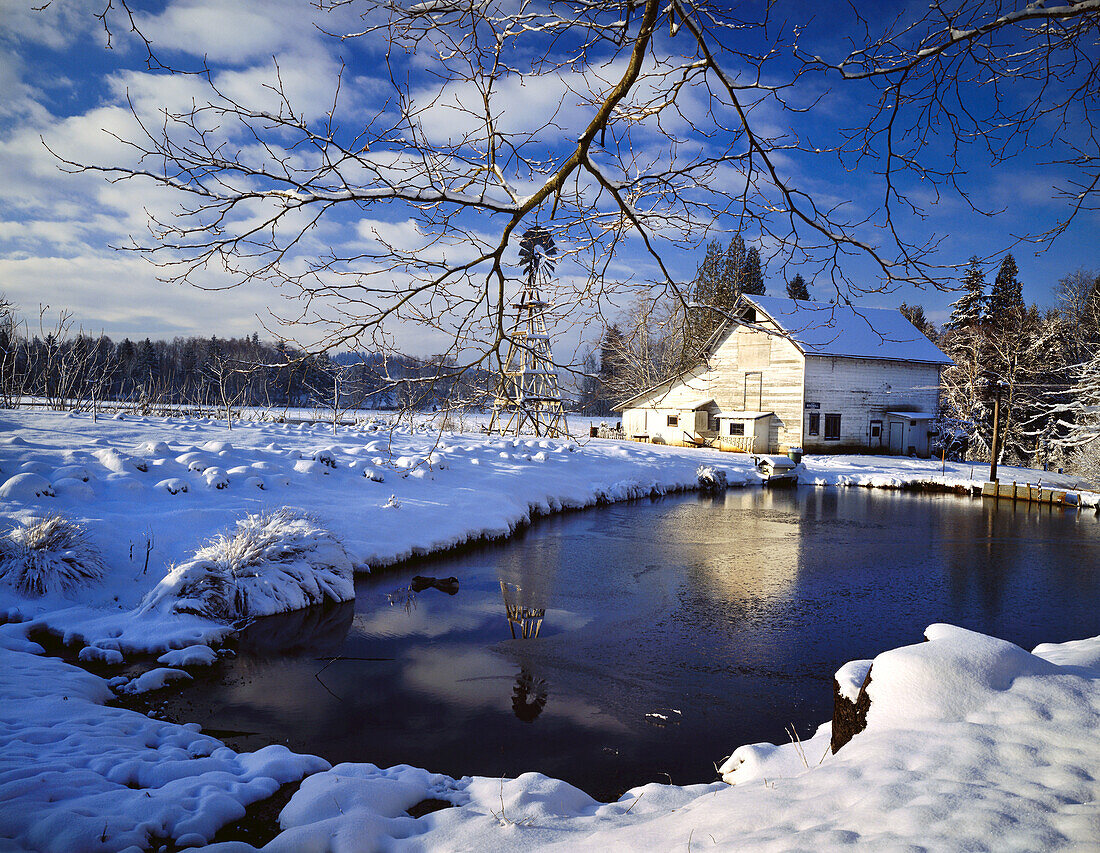 Verwitterte Scheune und Farmhaus an einem Teich im Winter mit schneebedecktem Feld in Columbia River Gorge National Scenic Area,Oregon,Vereinigte Staaten von Amerika