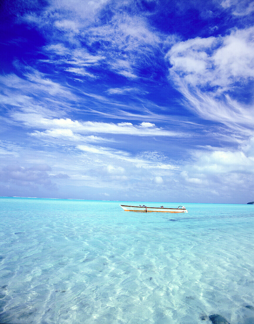 A rowboat sits in the tranquil turquoise water of the South Pacific Ocean in the Leeward islands,French Polynesia