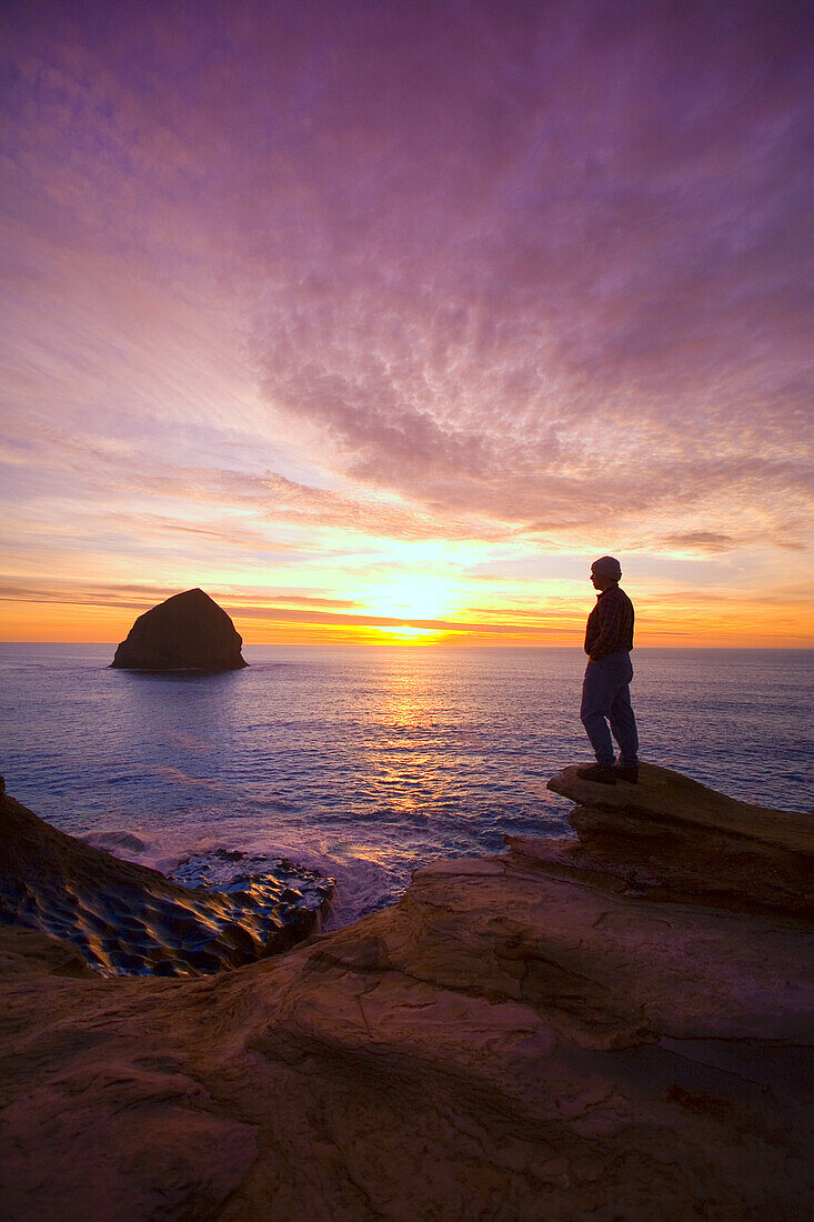 Silhouette eines Mannes mit Blick auf den Pazifischen Ozean bei Sonnenuntergang an der Küste von Oregon, Oregon, Vereinigte Staaten von Amerika