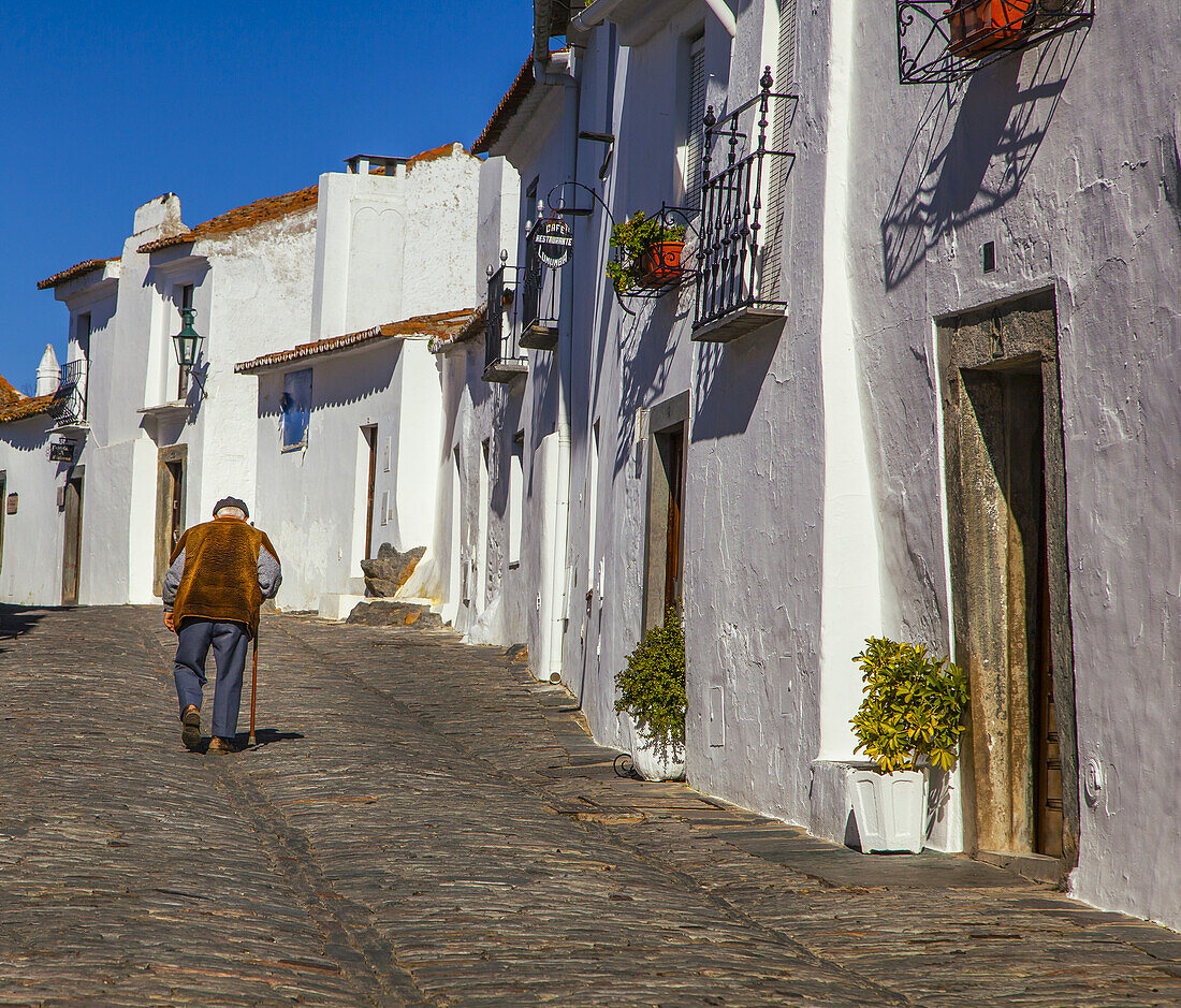 A senior man with a cane strolls on the cobblestone street in Evora,Evora,Portugal