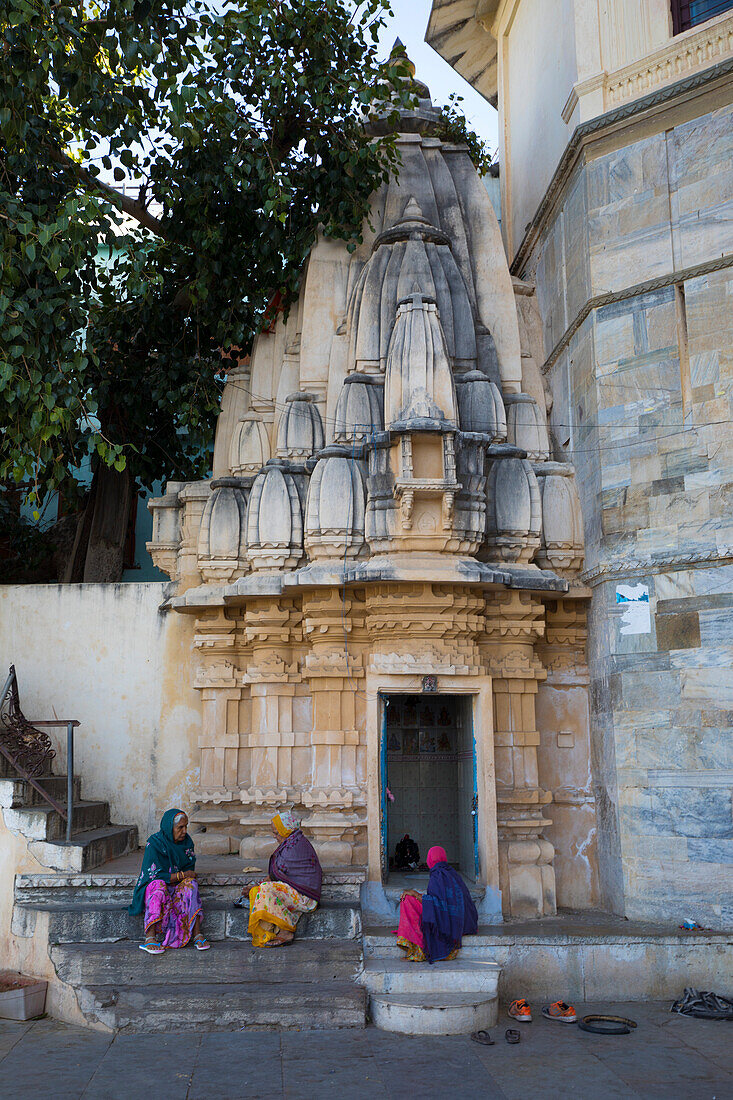 Drei Frauen sitzen in einem Hindu-Tempel am Ufer des Pichola-Sees, Udaipur, Rajasthan, Indien