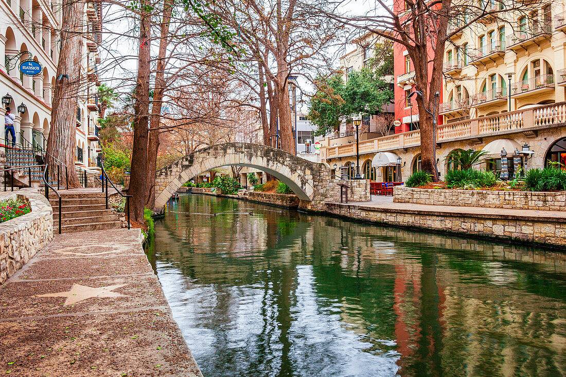 Gewölbte Fußgängerbrücke über den ruhigen San Antonio River auf dem San Antonio River Walk, San Antonio, Texas, Vereinigte Staaten von Amerika