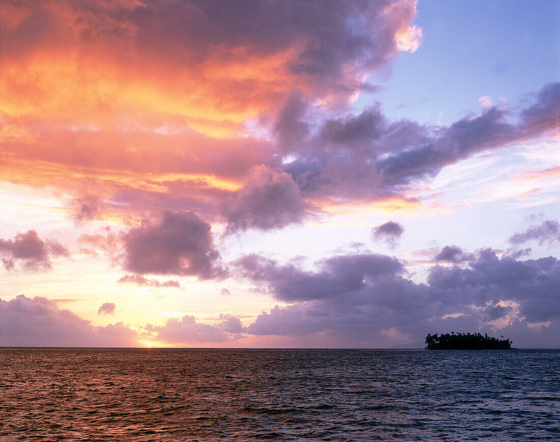 Glowing clouds over a tropical ocean and small island at sunset,Cook Islands