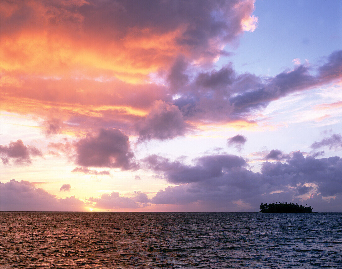 Glühende Wolken über einem tropischen Ozean und einer kleinen Insel bei Sonnenuntergang,Cook Inseln