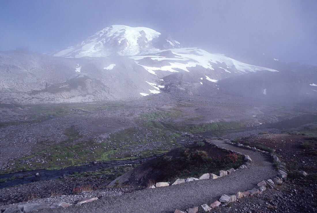 Fog settles in the valley in Mount Rainier National Park with a trail winding through the landscape,Washington,United States of America