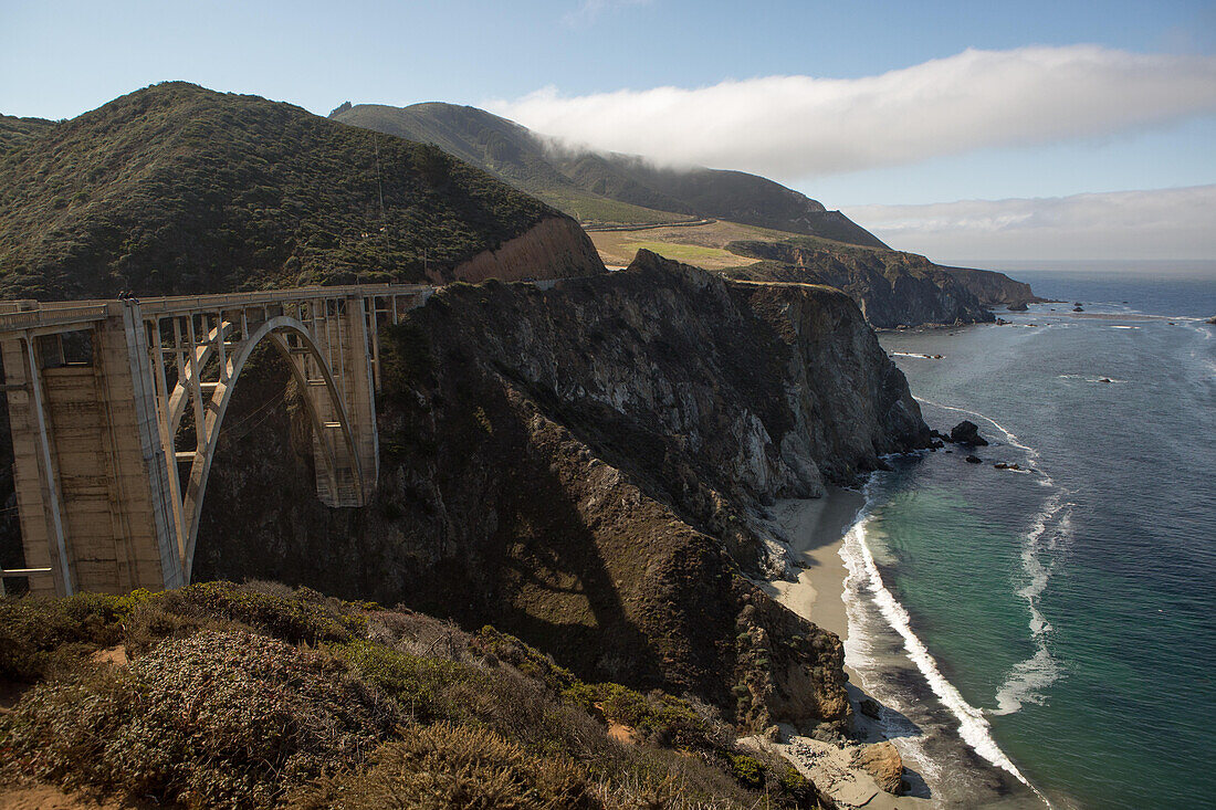 Several people sitting and sightseeing atop the Bixby Creek Bridge,a concrete,open-spandrel arch bridge,on the Pacific Coast Highway.,Bixby Creek Bridge,Pacific Coast Highway,California