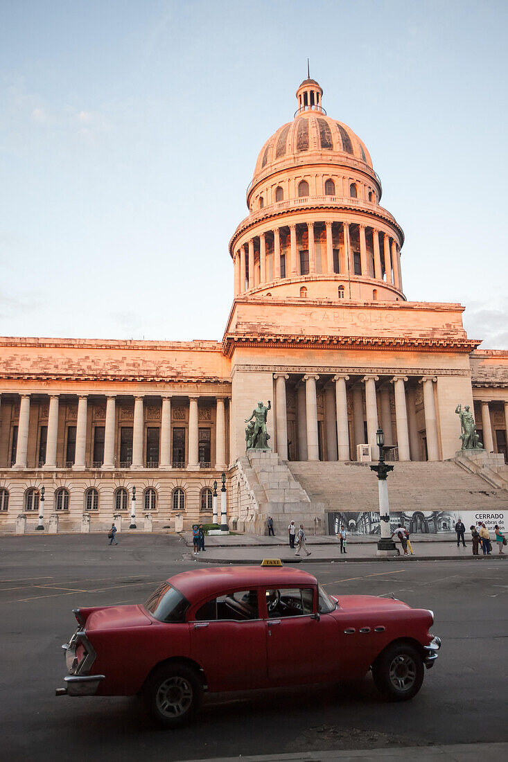 A classic American car drives past the El Capitolio Building in downtown Havana.,Havana,Cuba