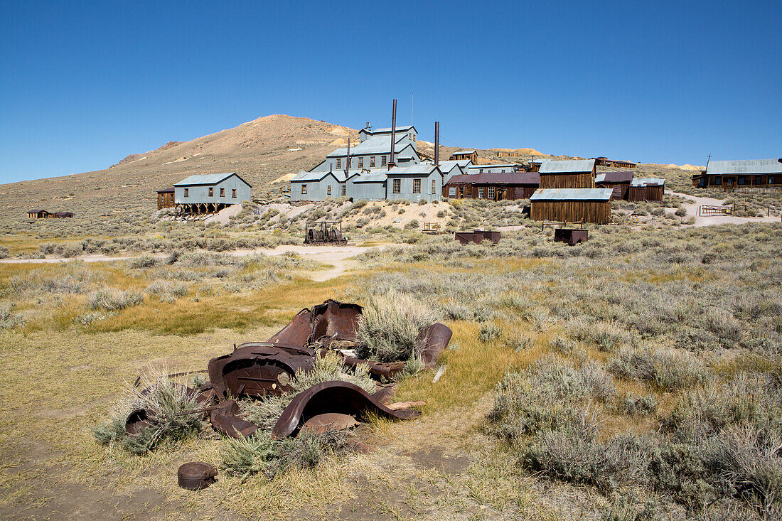 Der verfallende Metallrahmen eines antiken Fahrzeugs, das in der Nähe der Stempelmühle in Bodie Ghost Town teilweise im Boden vergraben ist,Bodie State Historic Park,Bridgeport,Kalifornien