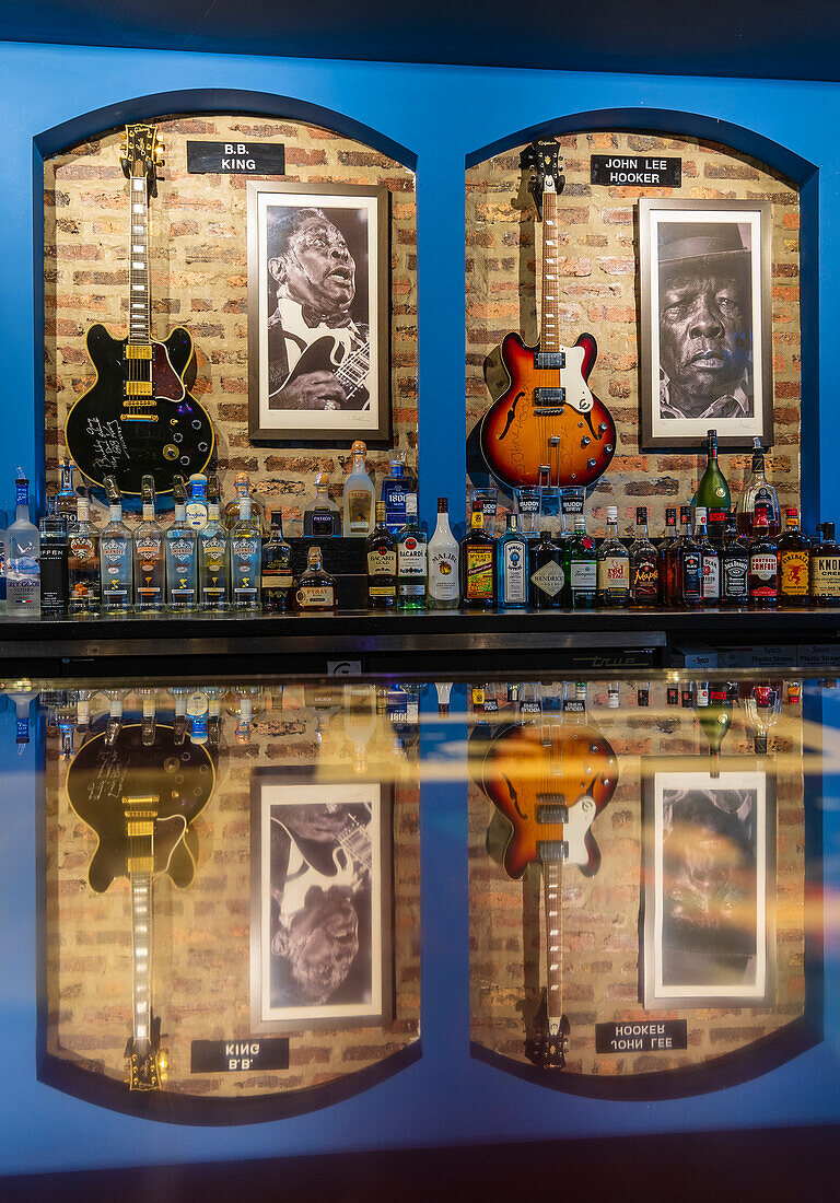 Anzeige von Fotografien und Gitarren von Blues-Musikern entlang einer Bar mit Alkoholflaschen in einem Blues-Club, Chicago, Illinois, Vereinigte Staaten von Amerika