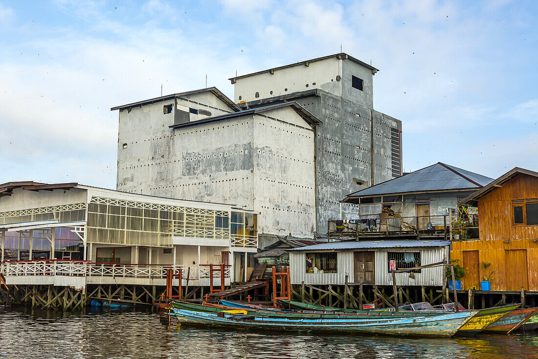 Gebäude und traditionelle Boote entlang des Ufers des Kumai River.