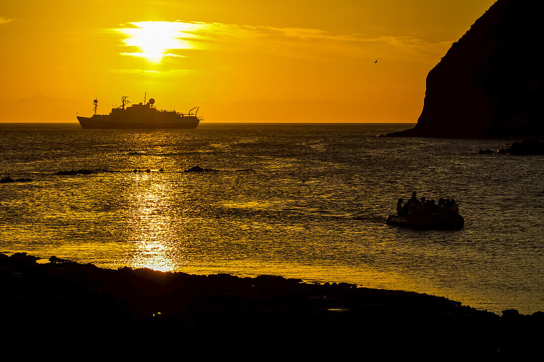 An inflatable boat and National Geographic Endeavour at sunset.