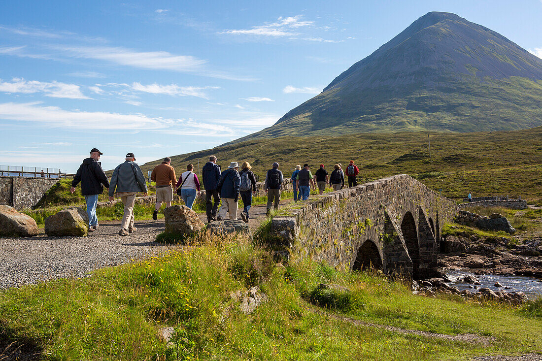 Wanderer überqueren eine Brücke, die zu einem Pfad durch die Cuillin Mountains bei Sligachan, Isle of Skye, Schottland, führt