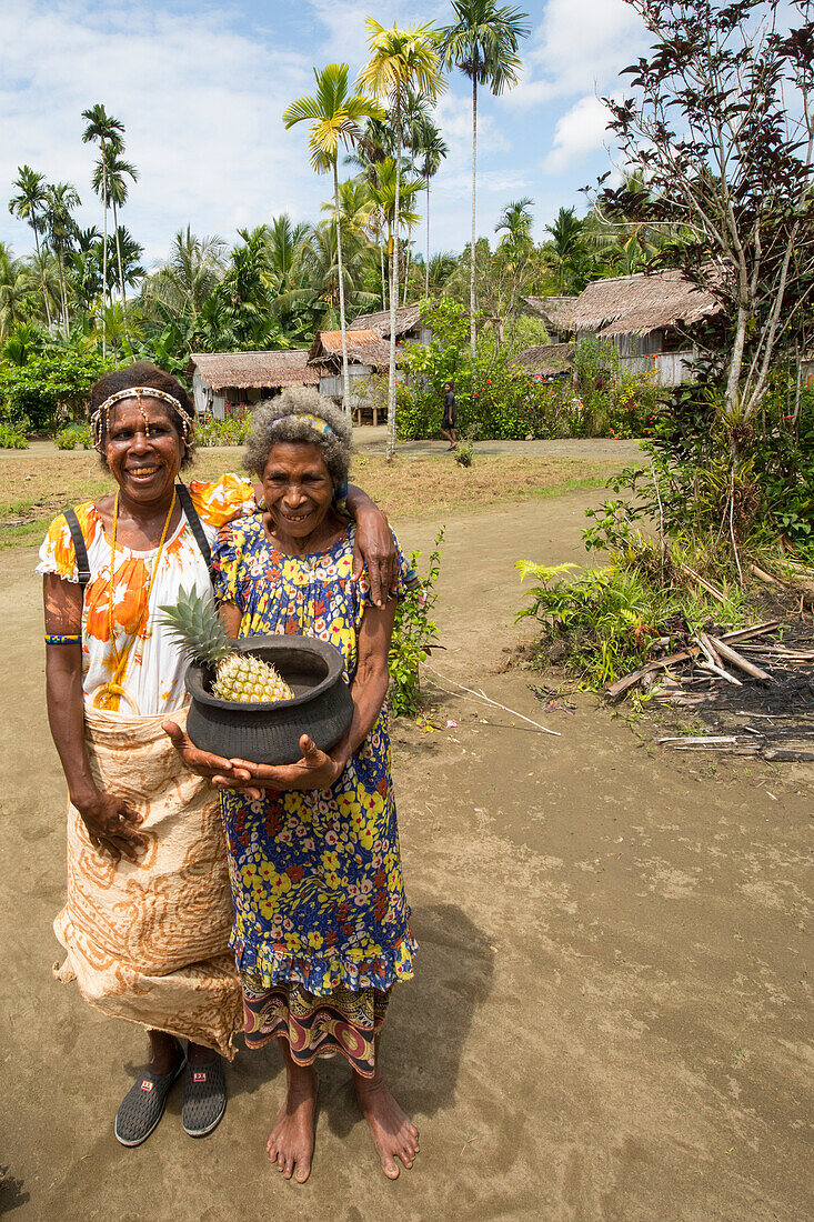 Zwei Frauen mit Ananas im Dorf Mou, Morobe Bay, Provinz Morobe, Papua-Neuguinea, Mou, Provinz Morobe, Papua-Neuguinea