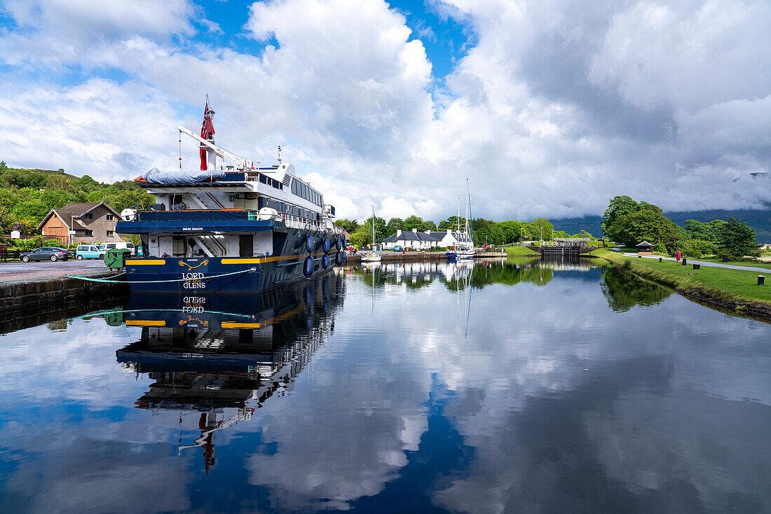 A small cruise boat docks along the Caledonia Canal near Corpach,Scotland,it's mirror image in the tranquil water,Corpach,Scotland