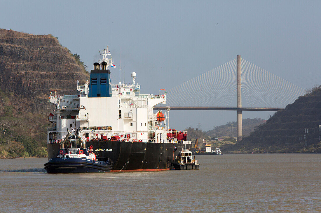 Tug boats guides a large vessel through the Panama Canal near Culebra Cut and the Centennial Bridge,Panama