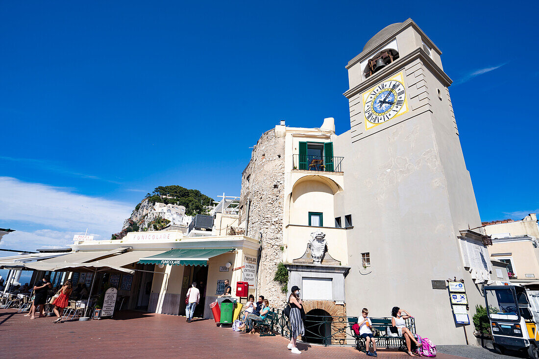 Uhrenturm und Fußgänger genießen einen sonnigen Tag auf der Insel Capri, Capri, Neapel, Italien