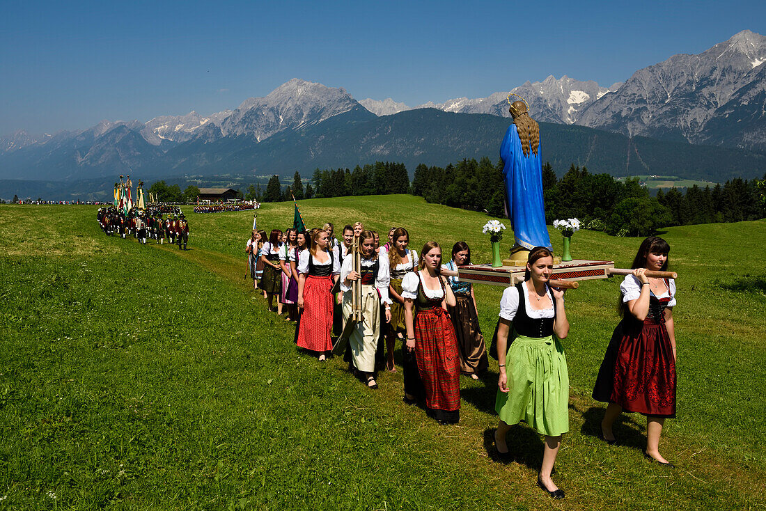 Der Festzug zum Herz-Jesu-Fest betritt eine große Wiese am Fuße des Karwendelgebirges.