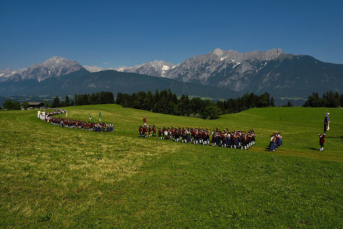 Der Festzug zum Herz-Jesu-Fest betritt eine große Wiese mit Blick auf das Karwendelgebirge.