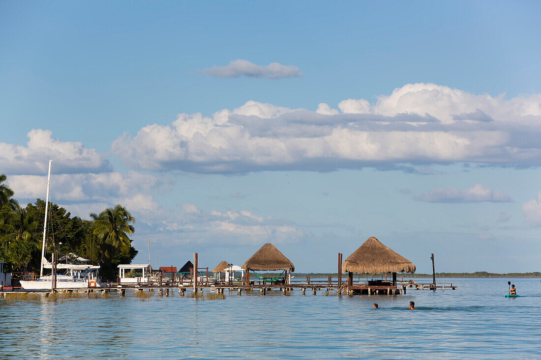 Docks an der Lagune von Bacalar, Mexiko, mit Touristen, die Freizeitaktivitäten genießen, Bacalar, Staat Quintana Roo, Mexiko