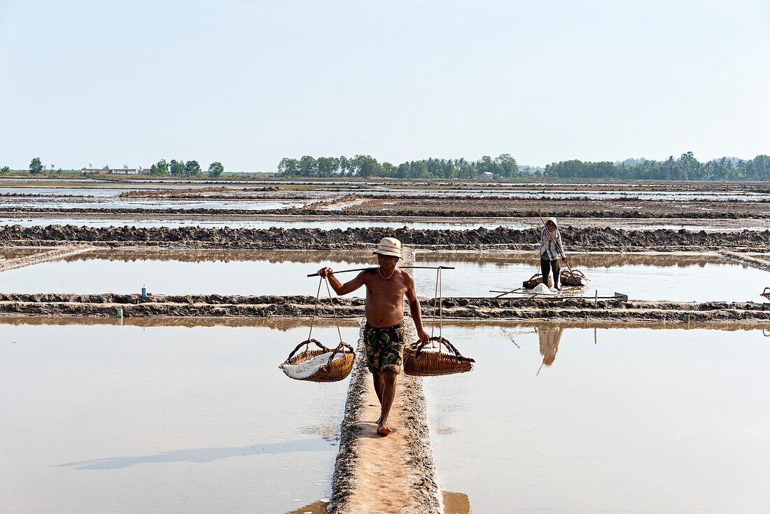 A man carries baskets of rice in a farming community in Southern Cambodia,Kampot,Cambodia