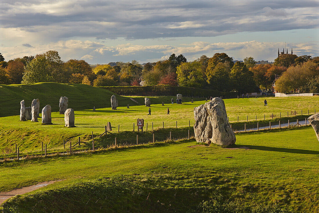 Touristen im Gras bei den prähistorischen Steinen in Avebury, Wiltshire, Großbritannien, Avebury, Wiltshire, England