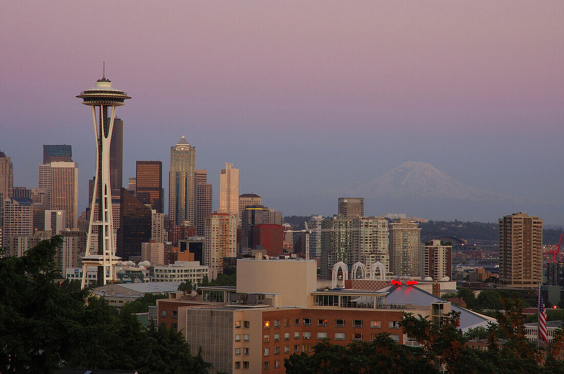 Die Skyline von Seattle (einschließlich der Space Needle) in der Abenddämmerung.  In der Ferne ist Mt. Rainier zu sehen,Seattle,Washington,USA