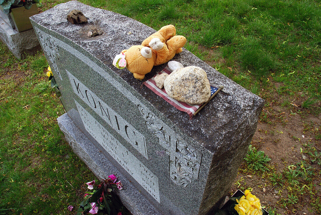 A gravestone decorated with memorabilia on Memorial Day.,Arlington,Massachusetts.