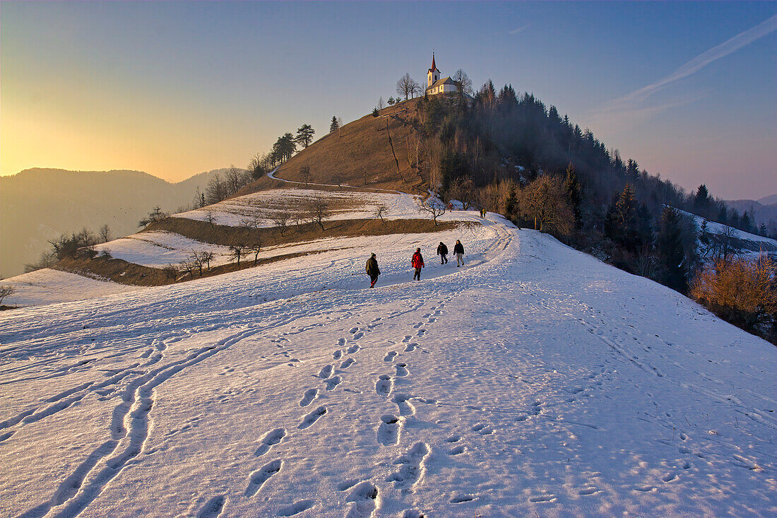 Slovenians walk along a snow-covered path to a hilltop church near Ljubljana,Slovenia