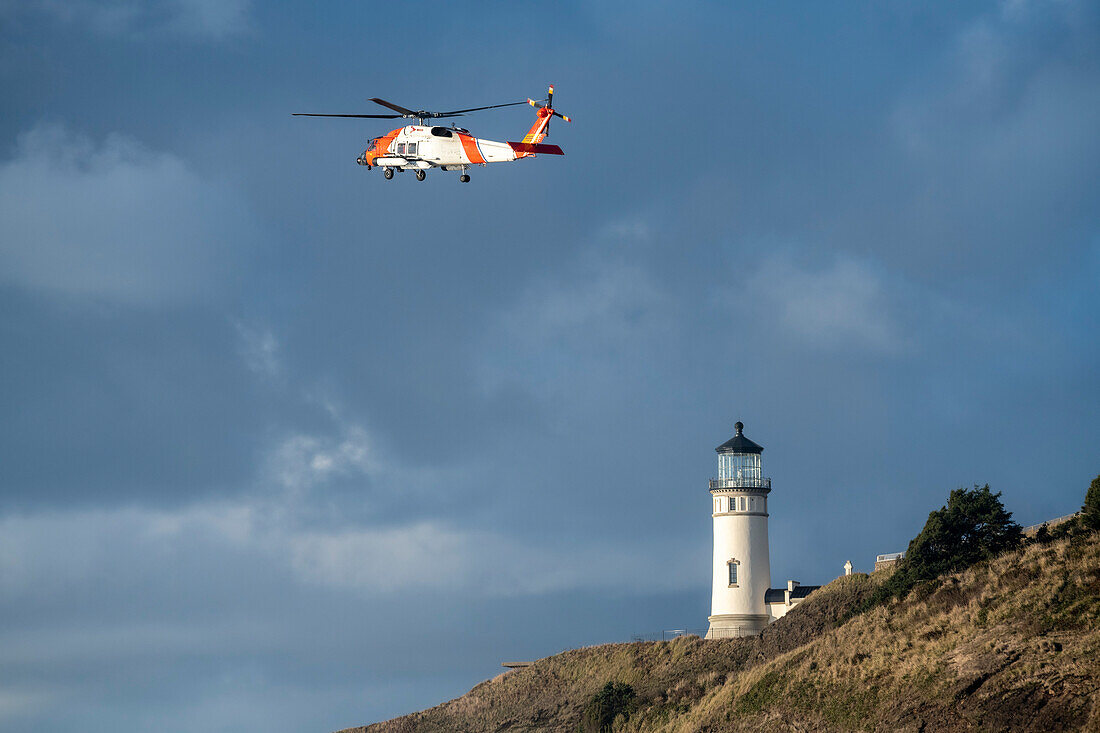 Hubschrauber der US-Küstenwache fliegt in der Nähe des Cape Disappointment North Head Lighthouse während eines Trainingseinsatzes, Ilwaco, Washington, Vereinigte Staaten von Amerika