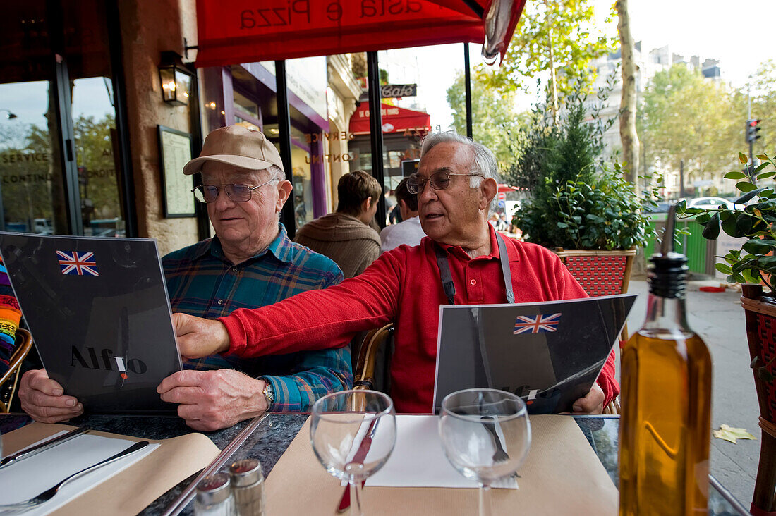 Two men look over menus at a restaurant in Paris,France,Paris,France