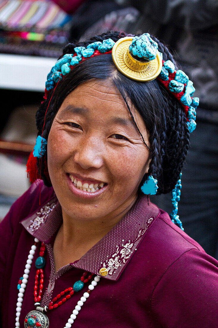 Lächelnde Frau mit Kopfschmuck auf dem Borkhar-Markt, Lhasa, Tibet