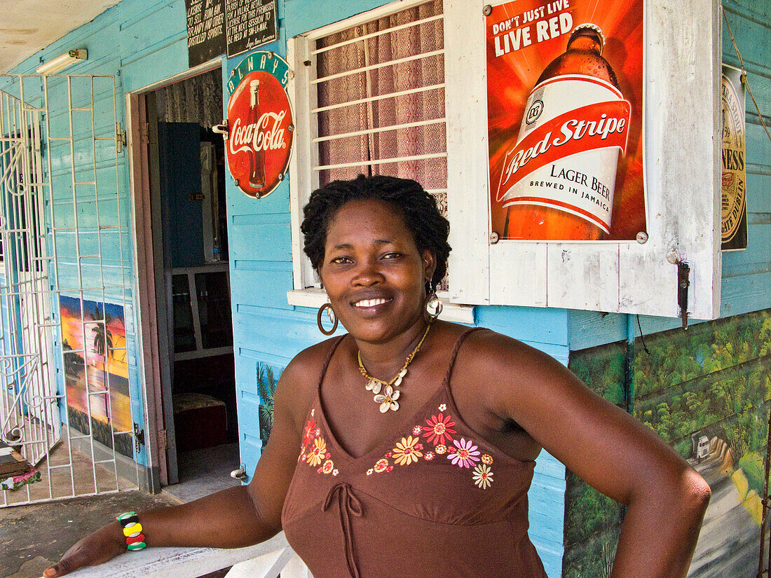 Barkeeperin mit Bier- und Cola-Werbung im Hintergrund, Bluefields Bay, Jamaika