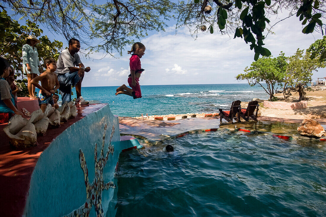 Kinder springen in einen Salzwasser-Pool am Strand eines jamaikanischen Resorts, Calabash Bay, Jamaika