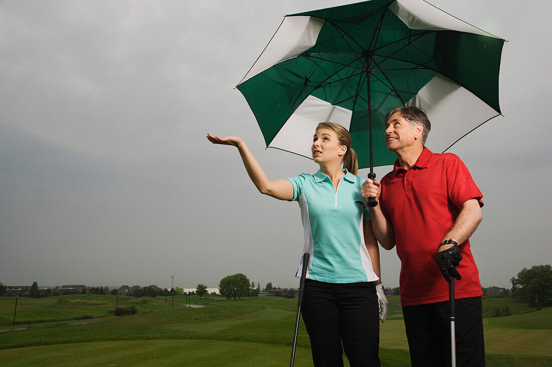 Father and Daughter on the Golf Course Holding a Large Umbrella