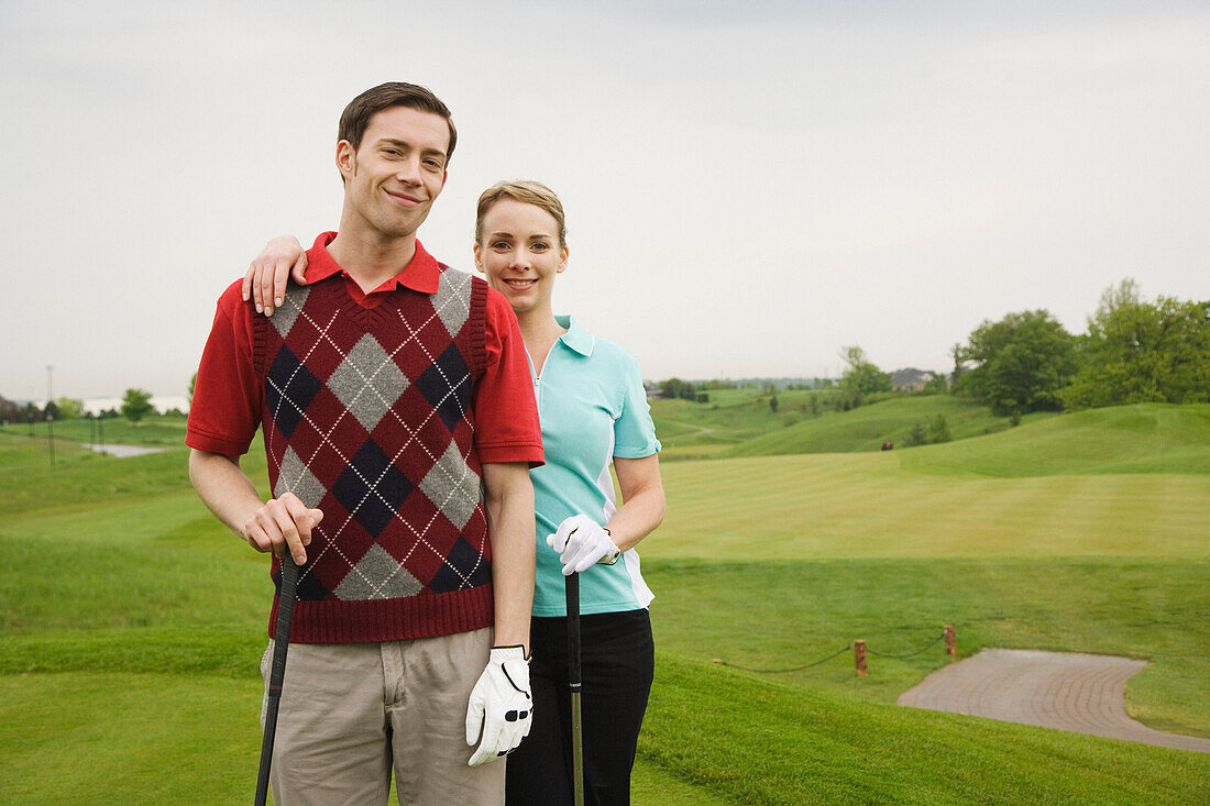 Porträt eines Paares auf dem Golfplatz stehend