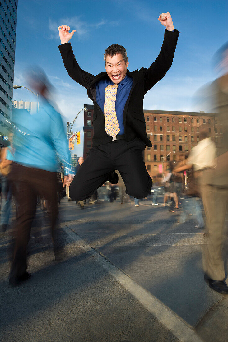 Geschäftsmann, der an einer Kreuzung in der Innenstadt vor Freude springt