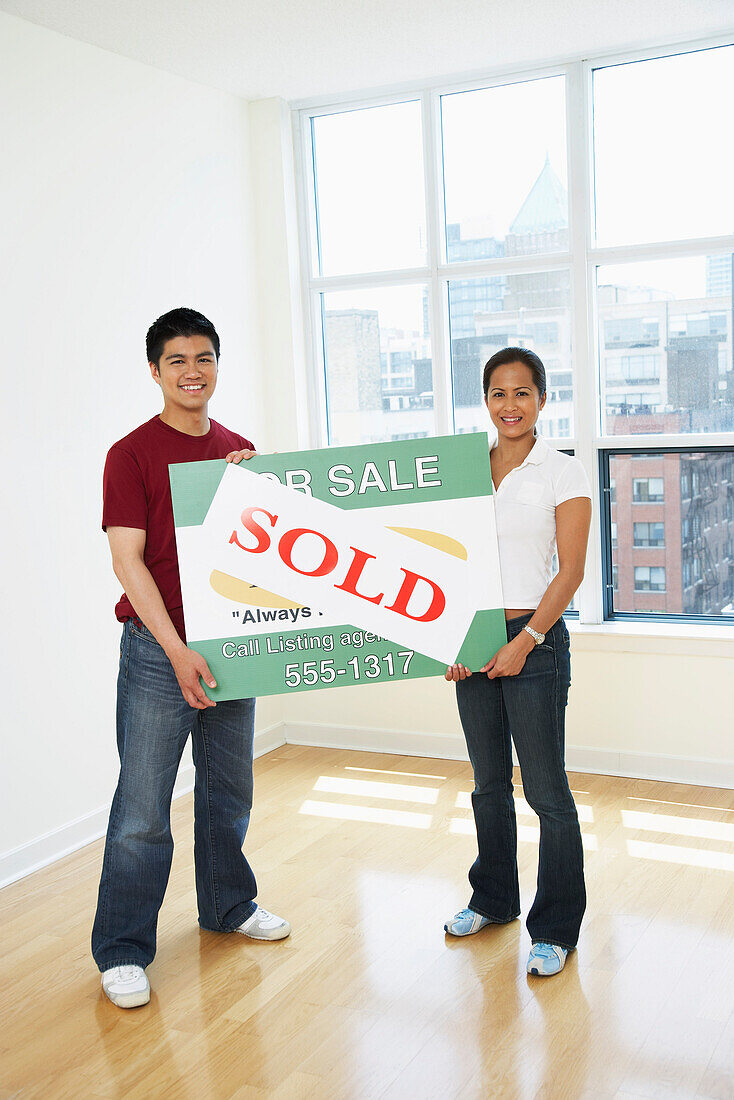 Couple Holding Sold Sign