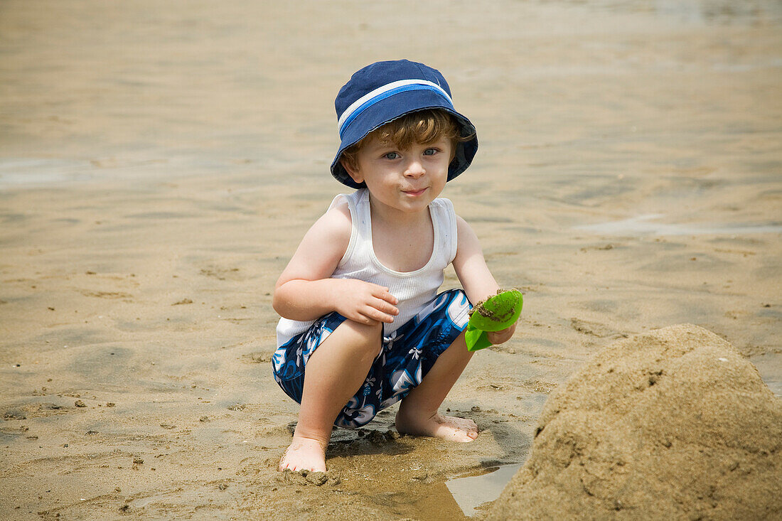 Porträt eines Jungen, der am Strand im Sand spielt