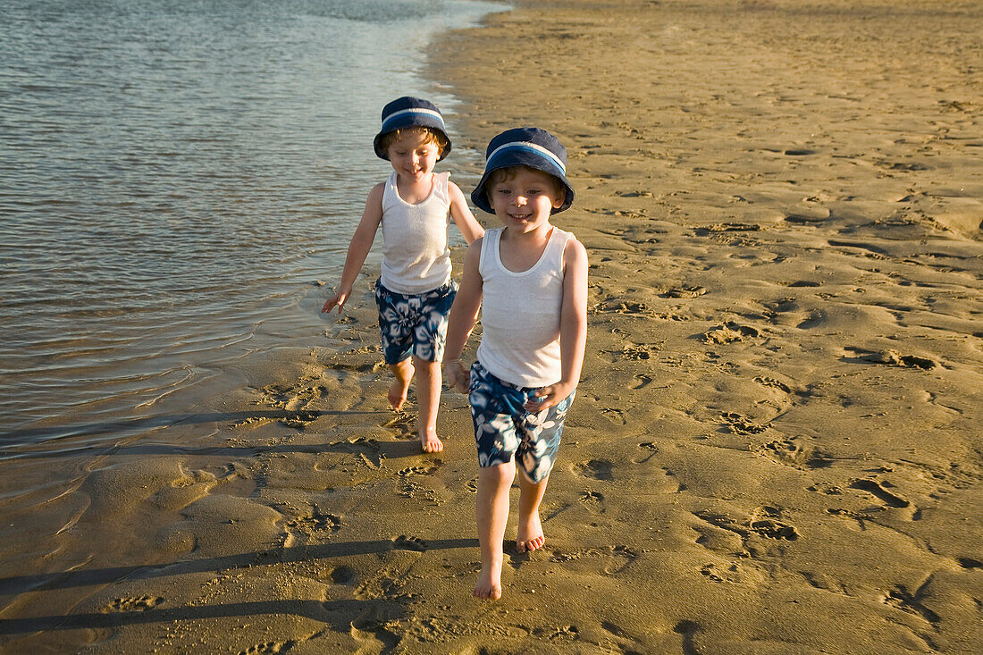 Zwillingsjungen gehen am Strand spazieren
