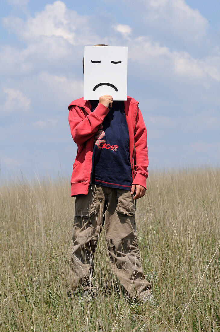 Junge im Feld mit Stirnrunzeln im Gesicht