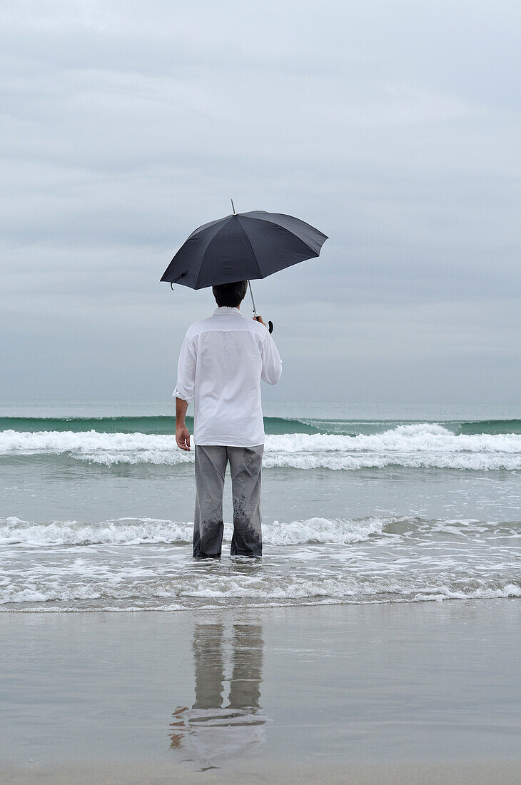 Man Holding Umbrella on Beach